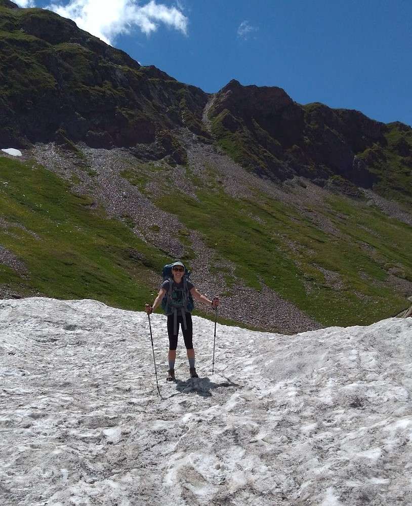 A hiker crosses a snow field on the TMB.