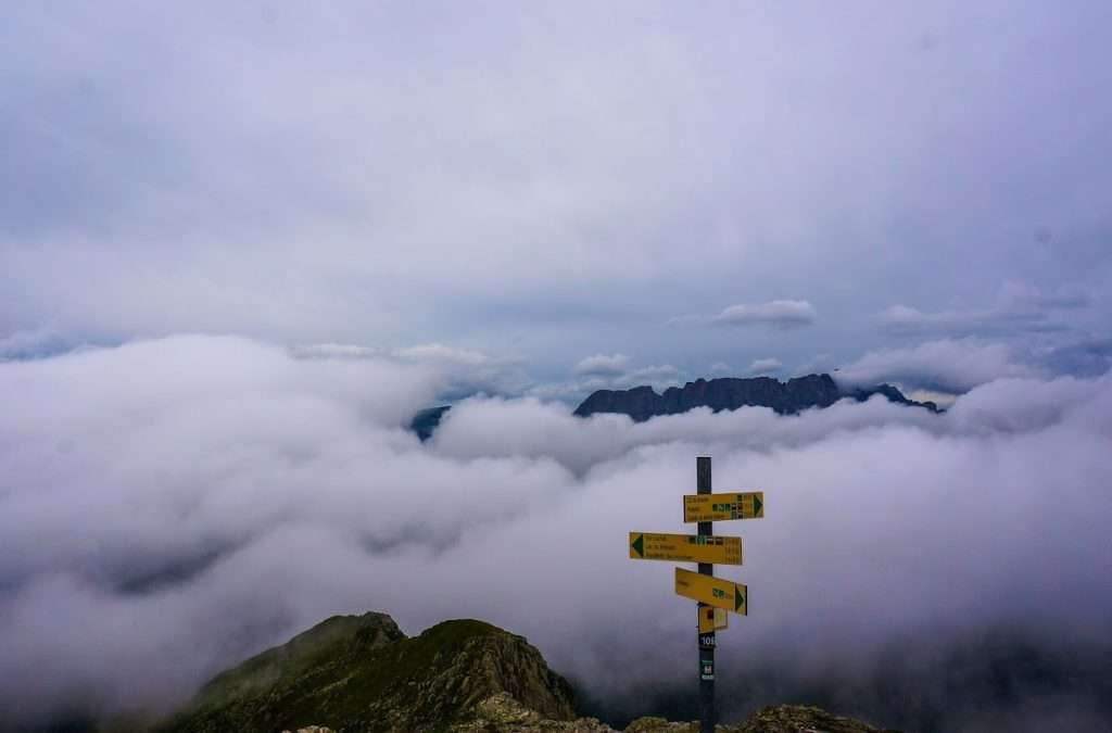 A trail sign with clouds behind it at Le Brevent.