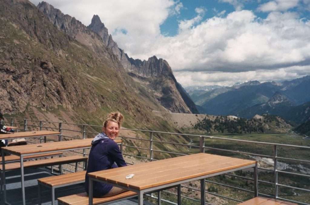 A woman sits at a picnic table on the terrace at Rifugio Elisabetta.