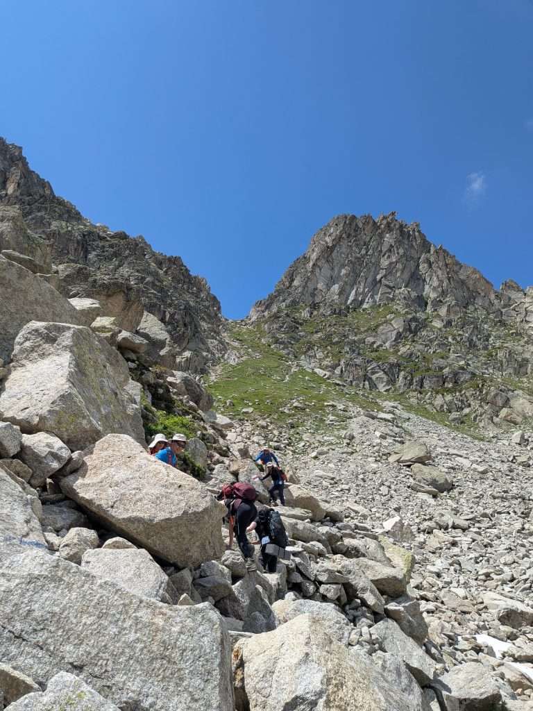 Hikers navigating a boulder field on the fenetre d'arpette.
